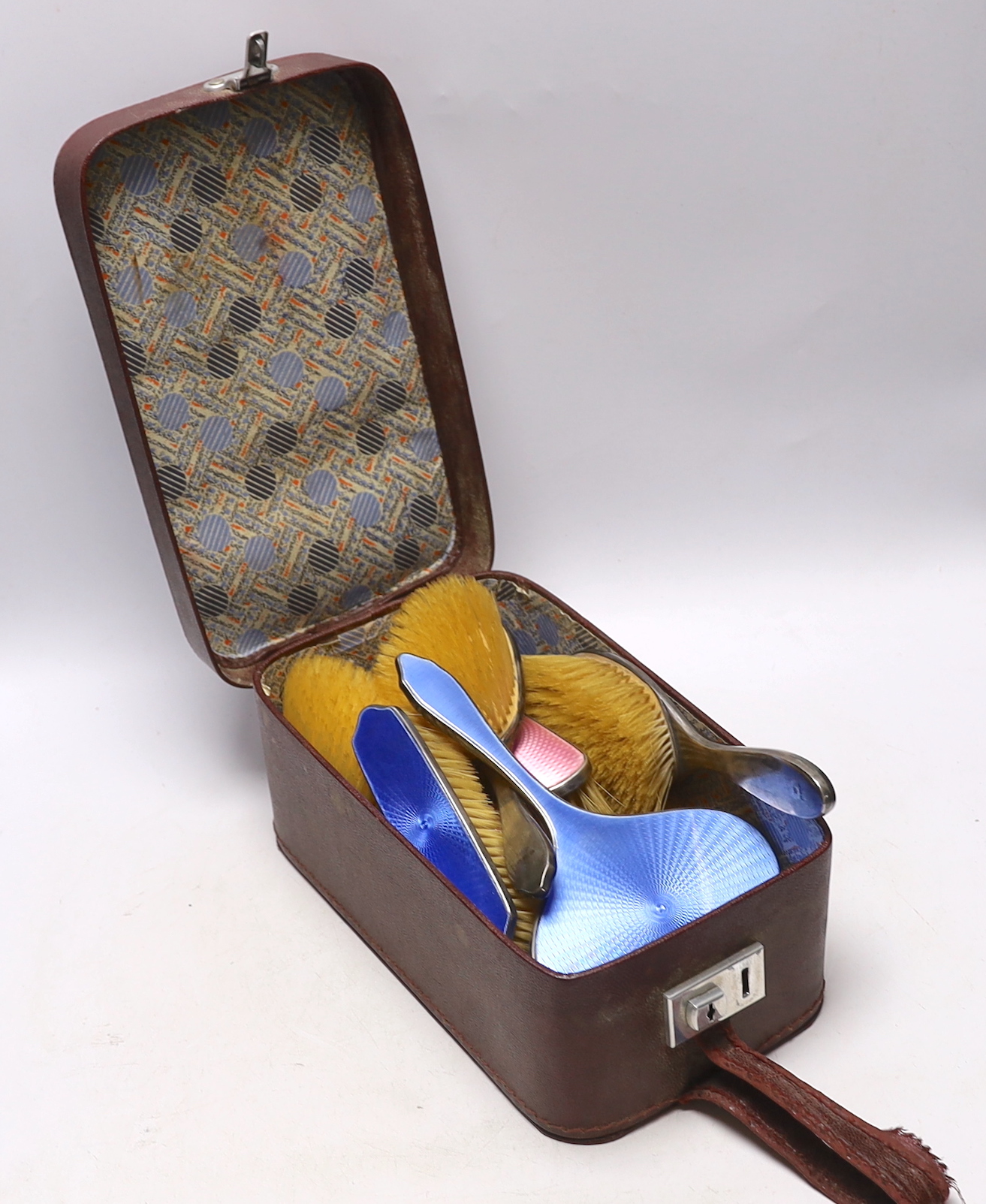 A George V silver and blue enamel five piece mirror and brush set, Birmingham, 1929 and a similar silver and pink enamel set, Birmingham, 1932.